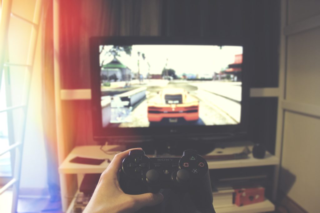 A person playing a driving video game animated on the tv. 